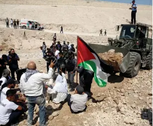  ?? (Mussa Qawasma/Reuters) ?? PALESTINIA­NS GATHER in front of a bulldozer on Friday as they protest Israel’s plan to demolish Khan al-Ahmar.