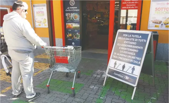  ?? PHOTOS: JAKE RUPERT ?? A shopper looks at the warning signs on social distancing outside a grocer in Torre de’Passeri, Italy, which former Ottawan Jake Rupert describes as a ghost town.