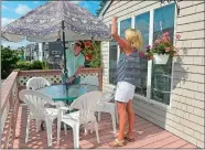  ?? SARAH GORDON/THE DAY ?? Jonathan Rodgers of Randall Realtors, left, helps Jenifer Egan of Mystic Home Staging set up an umbrella while staging a home for clients on Friday in Groton Long Point.