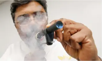  ?? LUKE MACGREGOR Bloomberg ?? KRISHNA Prasad, head of human studies at British American Tobacco, demonstrat­es a smoking analyser. Philip Morris launched its latest smoke-free product in South Africa yesterday. |