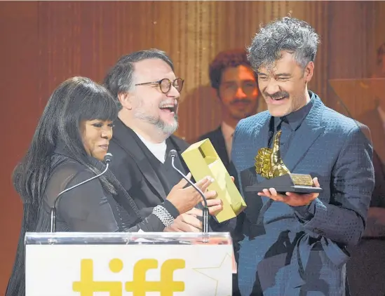 ?? Photo / Getty Images ?? Taika Waititi accepts the TIFF Ebert Director award from (from left) Chaz Ebert and Guillermo del Toro in Toronto.