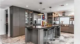  ?? ?? In the kitchen, dark-gray cabinets mix with dark stone counters and natural stone flooring for a rustic modern look.