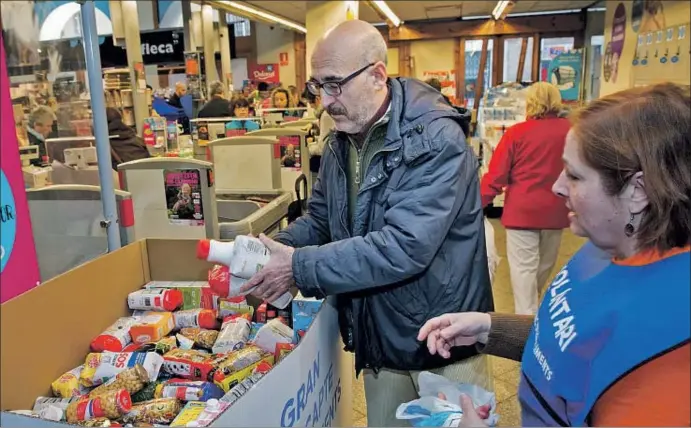  ?? GEMMA MIRALDA ?? Una voluntaria (con peto azul) indica a un ciudadano en qué lugar de la bañera puede depositar los alimentos donados, ayer en uno de los puntos de recogida