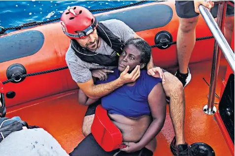  ??  ?? A crew member of the Proactiva Open Arms rescue boat embraces a traumatise­d woman who was rescued from the destroyed migrant boat