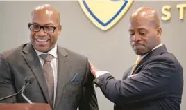  ?? AMY DAVIS/BALTIMORE SUN ?? Anthony L. Jenkins, president of Coppin State University, right, salutes Associate Professor Nicholas Eugene, left, who spearheade­d the $3.9 million federal grant for broadband access in West Baltimore that was announced Monday at the university.