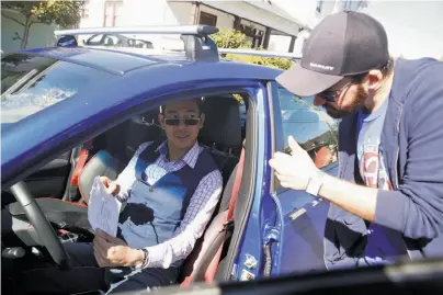  ?? Photos by Lea Suzuki / The Chronicle ?? Tyler Karon gives a thumbs-up as he picks up David Chu’s car in Alameda. He’s renting the vehicle through Turo.