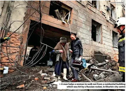  ?? ANDRII MARIENKO ?? > A man helps a woman to walk out from a residentia­l building which was hit by a Russian rocket, in Kharkiv city centre