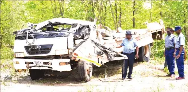  ??  ?? Tsholotsho South Member of Parliament Zenzo Sibanda and police officers view the wreckage of a Nissan UD truck that overturned and killed 21 people near Jimila Shopping Centre, Lucu Village, in Tsholotsho on Saturday. — (Picture by Obey Sibanda)