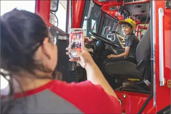  ?? ?? Chris Torres/The Signal Aryana Coulbourn takes a picture of her son Johnny, 7, in the Quint Fire Truck during the Los Angeles County Fire Department annual Fire Service Day in Los Angeles County Fire Station 126 in Valencia Saturday.