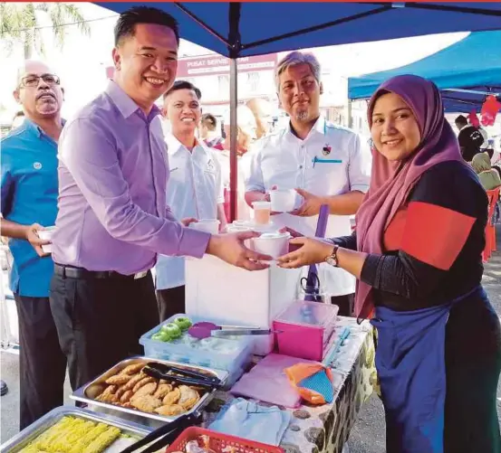  ?? PIC BY ABNOR HAMIZAM ABD MANAP ?? State Urban Wellbeing Committee, Local Government House and New Village chairman Teo Kok Seong (second form left) distributi­ng bubur lambuk to a trader at the Batu Kikir Ramadan bazaar in Jempol yesterday.