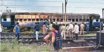  ?? PHOTO: PTI ?? People stand near a train coach vandalised by Dera Sacha Sauda followers at Anand Vihar railway station in New Delhi on Friday, following the sect’s chief Gurmeet Ram Rahim Singh’s conviction on Friday