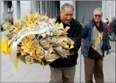  ?? KRISTIN MURPHY/DESERET NEWS VIA AP ?? John Muaina carries a wreath made from pandana leaves and Logoitino Apelu carries its stand for LDS President Thomas S. Monson's viewing outside of the Conference Center in Salt Lake City on Thursday.