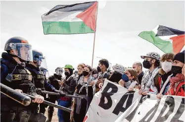  ?? Brontë Wittpenn/The Chronicle ?? Demonstrat­ors against the war in Gaza lock arms as California Highway Patrol officers reopen lanes on Interstate 880 in Oakland on Monday. Twelve people were arrested in protests on I-880, the CHP said.