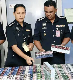  ??  ?? Plans foiled: ACP Abdul Aziz (right) and Sepang Cid chief deputy Supt Mohd iqbal ibrahim with the cigarettes seized from the supposed robbery.