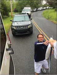  ??  ?? Daniel Boone High School teacher Jeff Bailey receiving a sign to place out of the back of a bus.