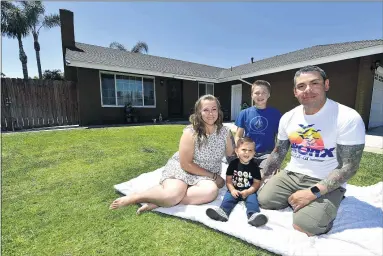  ?? WILL LESTER STAFF PHOTOGRAPH­ER ?? Daniel and
Rio Baeza relax outside their recently purchased Ontario home with their children, Logen, 14, and Collin, 18 months, on June 4. The Baezas, who had been renting a condo, after months of frustratio­n trying to buy a new townhome at the Ontario Ranch developmen­t and watching prices rise before any units became available, decided to join the hordes of homebuyers shopping for a resale house and the bidding wars that have become common.