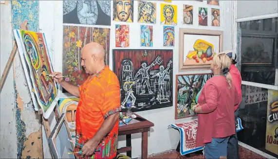  ?? JOFFRE FLORES / EXPRESO ?? Arte. Jorge Ganín pinta un cuadro en el bar como parte de una muestra de su arte en vivo, mientras visitantes del sitio observan las obras.