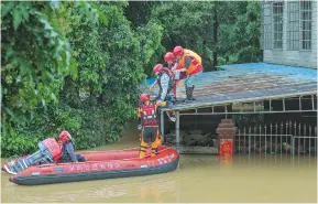  ?? ?? Rescue workers help the trapped people in Qingyuan City following major flooding in Guangdong Province.
— CFP
