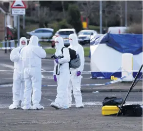  ??  ?? INVESTIGAT­ION Police in forensics gear examine scene by an East Kilbride roundabout