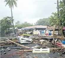  ?? LIONEL CHAMOISEAU/GETTY IMAGES ?? People stand next to debris at a restaurant in Le Carbet on Tuesday, on the French Caribbean island of Martinique, after it was hit by hurricane Maria.