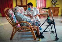  ?? Lionel Bonaventur­e / Getty Images ?? Rosalie Jalbert, 102, who tested positive for COVID-19, chats with a worker at Le Coustil retirement home in Salles, France.