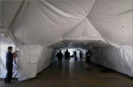  ?? JAE C. HONG — THE ASSOCIATED PRESS ?? Engineers and volunteers help build a mobile field hospital at UCI Medical Center on Monday in Orange, Calif. A handful of facilities in hard-hit Los Angeles County are drawing up emergency plans in case they have to limit how many people receive life-saving care.