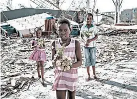  ?? YASUYOSHI CHIBA/GETTY-AFP ?? Girls collect artificial flowers from the rubble of a Beira, Mozambique, destroyed building.
