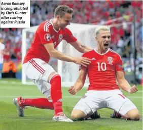  ??  ?? Aaron Ramsey is congratula­ted by Chris Gunter after scoring against Russia