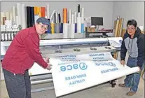  ?? NICK SMIRNOFF / FOR TEHACHAPI NEWS ?? South Street owners Audrey Post, in red, and Lydia Chaney operate their wide bed, banner printing machine.