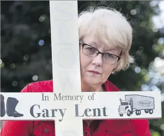  ?? DEREK RUTTAN ?? Kathleen Reed holds a cross that she had planned to post last October near the spot on Highway 401 where her partner Gary Lent was killed in a crash.