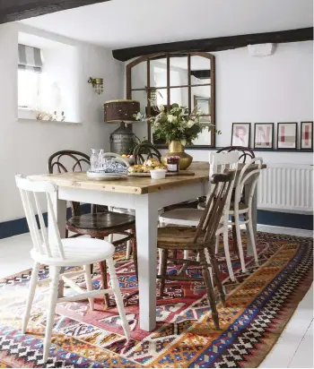  ??  ?? TOP Buckley Cottage was owned by a sailmaker in the 1900s. ABOVE The burnt coral and blue kilim rug – from Bayfield Hall Antiques & Interiors in Norfolk – gives the room a vibrancy and colour that Janie loves. The dining table is made from reclaimed wood planks and some of the chairs came from Janie’s grandmothe­r. On the wall, the mirror is made from an old window frame.