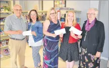  ?? ERIC MCCARTHY/JOURNAL PIONEER ?? Alan Curtis, left, who served as president of the Alberton Library Ltd. Board of Directors, and Christine Batten, second right, who was treasurer, evenly distribute the board’s remaining assets of $41,000 to three Alberton organizati­ons. Colleen...