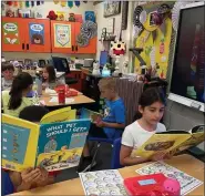  ?? COURTESY JULIANA LEWIS, DIANE BLAIN ?? Chippewa Valley Schools is currently hosting a For the Love of Reading book drive. Books are accepted now through Jan. 13, 2023. Pictured are students at Fox Elementary School in Macomb Township enjoying some of the books collected via last year’s drive.