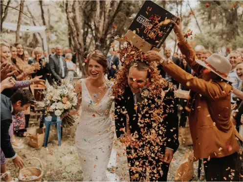  ??  ?? ABOVE
The couple’s favourite image of the petal tossing. ‘But when we say tossing I mean the petal “dumping”... The colours, the faces on the guests, our faces of absolute joy and just the spontaneit­y of it all was priceless.’