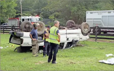  ?? Doug Walker / Rome News-Tribune ?? Cpl. Brenton Whatley (from left) and firefighte­rs John Galbreath and Todd Lanier survey the scene of a one-vehicle wreck Sunday evening off Old Dalton Road. The passenger in this Ford F-350 was taken to Redmond Regional Medical Center.