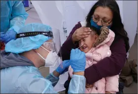  ?? (AP/Rick Bowmer) ?? Kim Tapia holds her granddaugh­ter Amariah Lucero, 3, while she gets a coronaviru­s test Tuesday at the Utah National Guard’s mobile testing site in Salt Lake City.