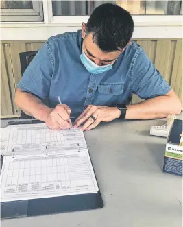  ?? NICOLE SULLIVAN • CAPE BRETON POST ?? Wilhelmus van Hal, recreation director at Maple Hill Manor, checks boxes on the questionna­ire everyone must fill out before visiting a resident outdoors.