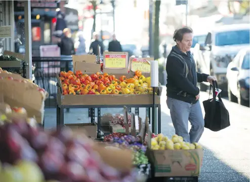  ?? ARLEN REDEKOP/PNG ?? A shopper picks up produce on Commercial Drive. Vegetable prices are projected to rise in 2019.