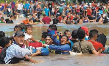  ?? Jeff Abbott For The Times ?? MIGRANTS hold one another Monday as they cross the Suchiate River separating Guatemala and Mexico.