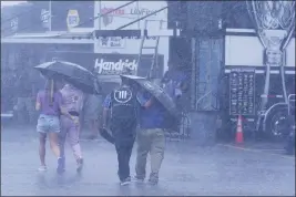  ?? MARK HUMPHREY — THE ASSOCIATED PRESS ?? People walk through the track garage area during a rain shower before a NASCAR Xfinity Series auto race Saturday in Lebanon, Tenn.