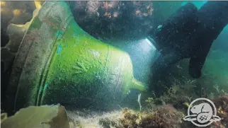  ?? THIERRY BOYER /PARKS CANADA ?? Parks Canada’s Filippo Ronca shines his light on the ship’s bell of HMS Erebus as it lies on the bottom in Nunavut’s Arctic waters.