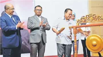  ??  ?? Entulu (right) strikes a gong to launch the carnival as Idris (second left) and Melaka state secretary Datuk Seri Naim Abu Bakar (left) look on. — Bernama photo