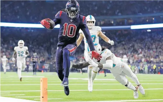  ?? TIM WARNER/GETTY-AFP ?? The Texans’ DeAndre Hopkins catches a pass and runs for a touchdown through the grasp of the Dolphins’ Bobby McCain during the fourth quarter Thursday night in Houston.