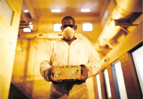  ?? SIMON DAWSON/BLOOMBERG FILES ?? A worker holds a 22-kilogram gold bar at Randgold Resources Ltd.’s Kibali gold mine in Kibali, Democratic Republic of Congo. Toronto-based miner Barrick Gold Corp. announced on Monday a US$6-billion plan to purchase Randgold. The deal is expected to close in 2019.