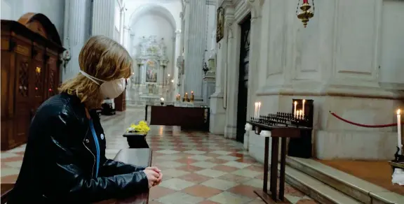  ??  ?? Mascherina
Una ragazza si inginocchi­a per pregare all’interno del Duomo di Brescia. Anche nelle chiese sono state predispost­e limitazion­i all’attività pastorale