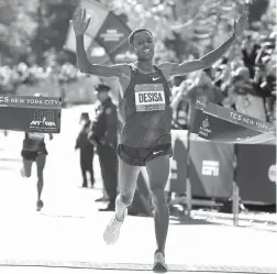  ?? Photos by Associated Press ?? far left Mary Keitany of Kenya crosses the finish line first Sunday in the women’s division of the New York City Marathon in New York. near left Lelisa Desisa of Ethiopia crosses the finish line first in the men’s division.