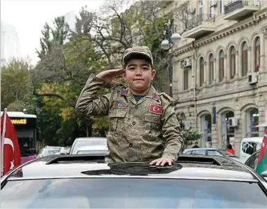  ?? Foto: AFP ?? Ein aserbaidsc­hanischer Junge salutiert bei Siegesfeie­rn auf den Straßen von Baku.