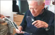  ?? FANG YIXIAO / XINHUA ?? Mitsushige Maeda, who celebrated his 100th birthday last year, examines photograph­s that were taken during the Japanese invasion of China.