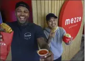  ?? MINDY SCHAUER — STAFF PHOTOGRAPH­ER ?? Aaron Cortez, left, and Justin Chang, two of the owners of Mezzo Calzones in Costa Mesa, display some of the fare they serve up — calzones, dipping sauce and pasta salad.