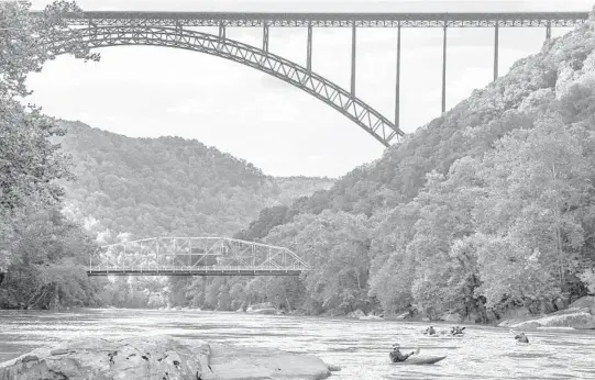  ?? TONY CENICOLA/THE NEW YORK TIMES PHOTOS 2018 ?? Kayakers paddle under the New River Gorge Bridge in Fayettevil­le, West Virginia. The gorge boasts millions of years of geological history.